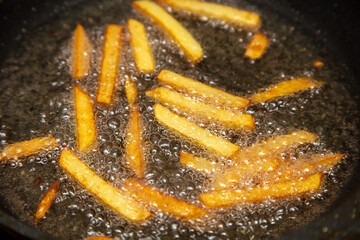 French fries are fried in oil in a pan.