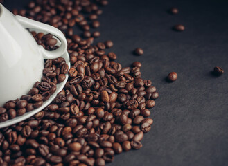 inverted white cup on a platter and sprinkled coffee beans on a dark background