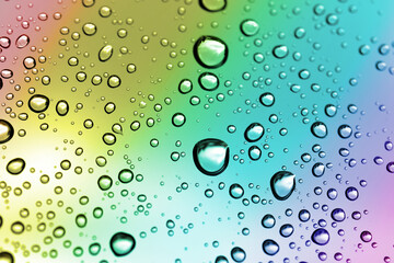 Water drops on a window glass after the rain. Nature background in rainbow color.