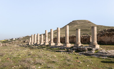 Fototapeta na wymiar The remains of columns in ruins of palace of King Herod - Herodion, against background of filled artificial hill in which they are located palace of King Herod - Herodion, in Judean Desert, in Israel
