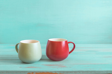 Two mugs on emerald wooden background with copy space.