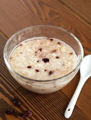 a glass bowl of oatmeal on wooden background closeup, minimal rustic design, healthy nutrition, fast breakfast of instant porridge with freeze-dried berries