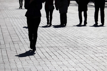 Fototapeta premium Silhouettes and shadows of people walking on the city street. Concept of society or population