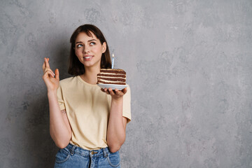 Portrait of happy woman holding cake and fingers crossed