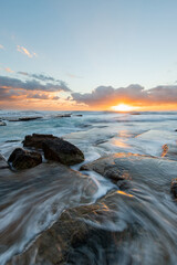Seawater flowing on the shore at sunrise time.