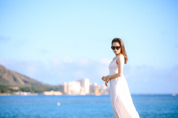 Fototapeta na wymiar Girl wearing white long dress by the sea, Honolulu, Oahu, Hawaii