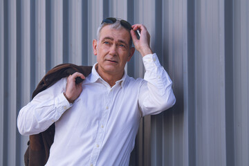 adult man with jacket on his shoulder and sunglasses on blind background