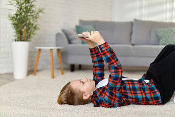 smiling child boy in checkered shirt using digital tablet at home