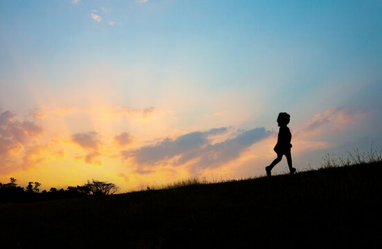 The silhouette of a girl running on the hill at sunset