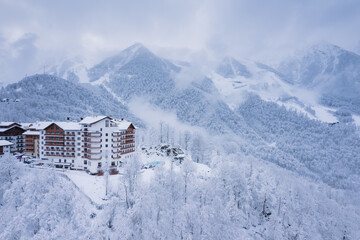 Winter aerial view of the Ski Resort Rosa Khutor. A complex of hotels on the site of the former Olympic village of Rosa Plateau at an altitude of 1170 m from sea level. Krasnaya Polyana, Sochi, Russia - obrazy, fototapety, plakaty