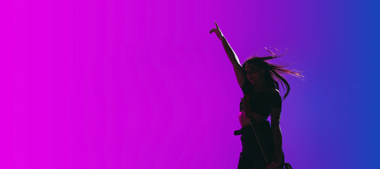 Silhouette of young female guitarist isolated on gradient background in neon.