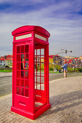 Porto Travel Destinations. Traditional Red Public Call Box in Porto City in Portugal At Daytime with Line of Houses on Background