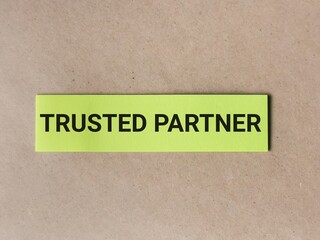 Business concept. Phrase TRUSTED PARTNER written on sticky note isolated on wooden background.