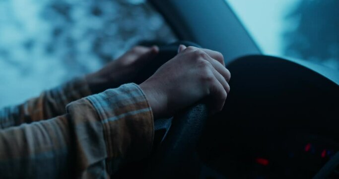 Cinematic and moody atmosphere shot of woman drive through dark foggy forest. Female hands hold steering wheel of car. Wanderlust roadtrip lifestyle concept. Vanlife adventure