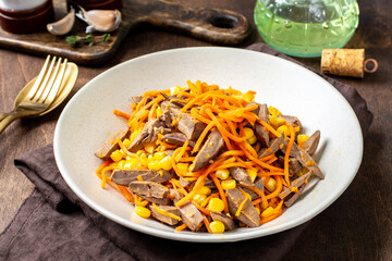 Turkey hearts, carrots and corn salad in a plate on a brown wooden background closeup. Healthy eating
