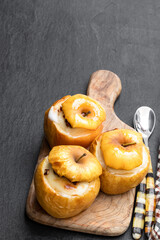 Baked apples stuffed with soft cheese and nuts on black stone background
