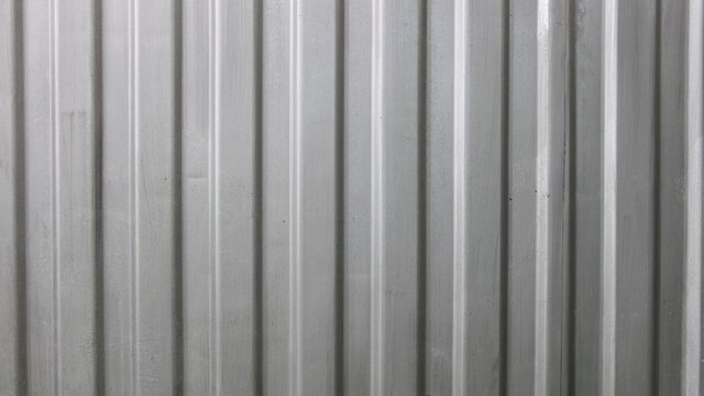 Gray painted metal corrugated sheet fence surface vertical lines industrial texture background