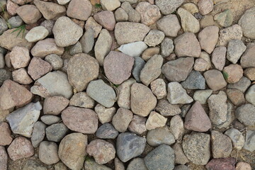 Old ancient stone pavement of red, gray and white cobblestone background texture 