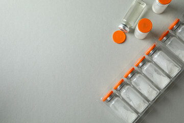 Vials with powder and liquid vaccine on light gray background