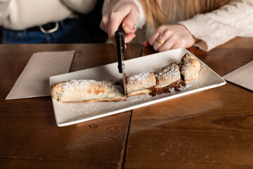 Fototapeta na wymiar a girl's hand cuts a dessert made of pizza dough with chocolate cream