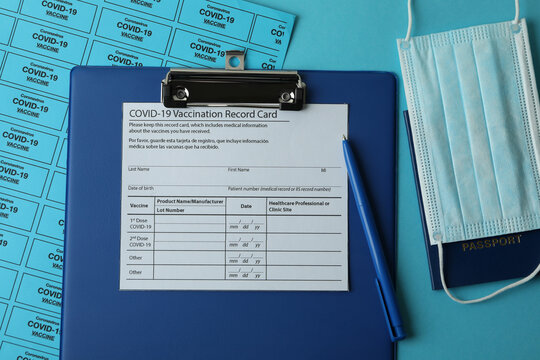 Covid - 19 Vaccination Concept With Record Card, Mask And Passport On Blue Background