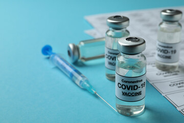 Concept of Covid - 19 vaccination with vials and syringe on blue background