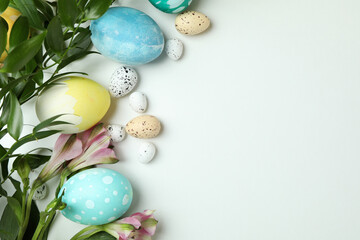 Obraz na płótnie Canvas Easter eggs and beautiful flowers on white background, space for text