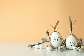 Easter bunnies made of eggs, quail eggs and catkins against beige background