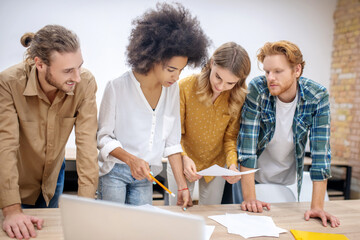 Group of young professionals working on the project together and looking concentrated