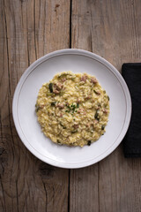 plate of risotto with sausage and zucchini on table with raw boards