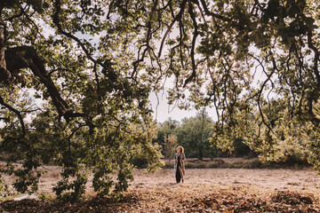 Girl with curly hair under an oak tree.