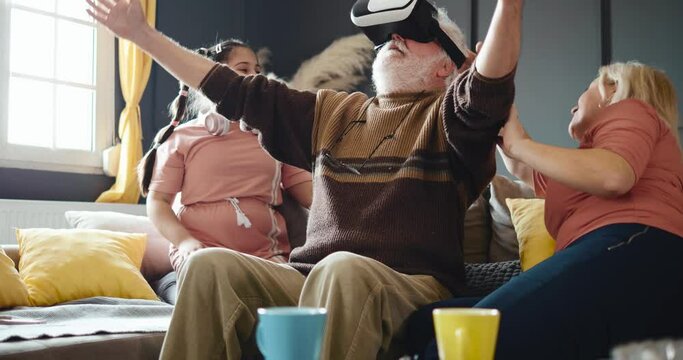 Active Grandpa uses VR glasses for a virtual world of games, exploration and travel. The little girl shows her grandparents to use VR