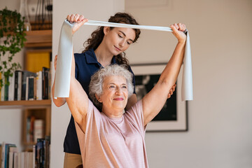 Senior patient doing exercise with elastic band at home with personal trainer