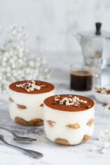 Tiramisu. Traditional italian dessert in a glasses with a cup of espresso coffee. Marble background.