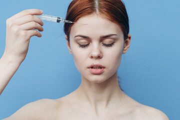 woman makes a rejuvenating injection in the face on a blue background and a syringe with a botox needle