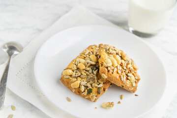 Homemade cookies with cereals and nuts with milk on a marble table.