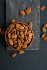 Almonds nuts close-up in a  wooden cup on a black shabby chic board on a black schiffer  background.Nuts and seeds. .Healthy fats.Heap Almonds shelled  nut closeup.Tasty organic snack 