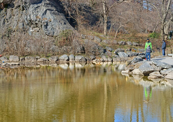 Central Park on sunny day in early spring. Rocky shores of lake. New York City