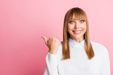 Portrait of young happy positive cheerful good mood woman pointing thumb copyspace isolated on pink color background