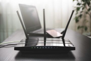 WIFI router connected to the internet on table and laptop in the background - obrazy, fototapety, plakaty