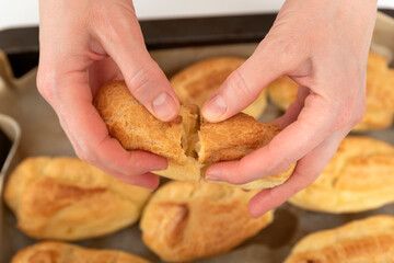 Middle of workpiece for profiteroles in hands of Chef. Puffs, popovers, eclair. Close up.