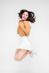 happiness, freedom, motion and people concept - smiling young woman jumping in air over gray background
