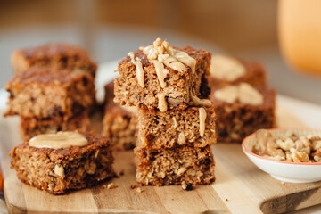 Homemade banana bread loaf with walnuts sliced on wooden cutting board overflowed with peanut butter. Close Up view, horizontal