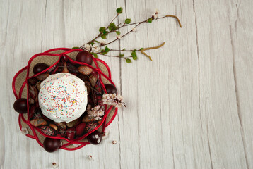 Easter composition. A blooming apricot branch, spring birch branches, painted eggs and a glazed Easter cake on a light wooden background. Happy Easter Holidays. Top view. Free space.