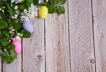 Easter composition. A border of flowering apple branches and colorful eggs on a wooden background. Happy Easter Holidays. Free space.
