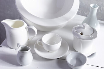 Obraz na płótnie Canvas Empty crockery or ceramic dishes set. White kitchen dishware and tableware at wooden old chair