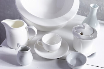 Empty crockery or ceramic dishes set. White kitchen dishware and tableware at wooden old chair