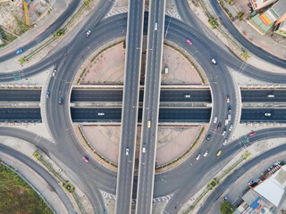 Aerial view of road intersection with roundabout. Urban highway interchange with cars speeding....