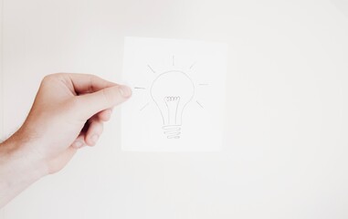 A man holding a paper with drawing on light bulb