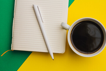 coffee cup on colored background and notepad pen top view office